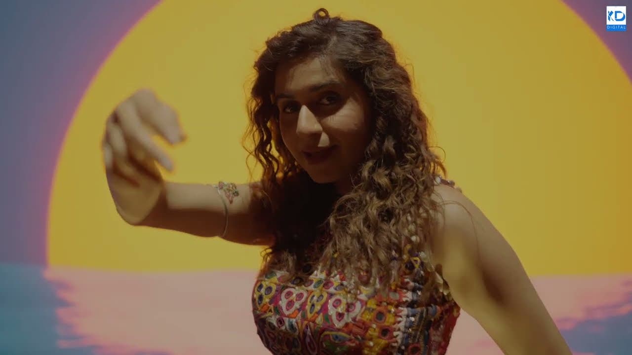 Kinjal Dave dancing in front of a yellow sun backdrop