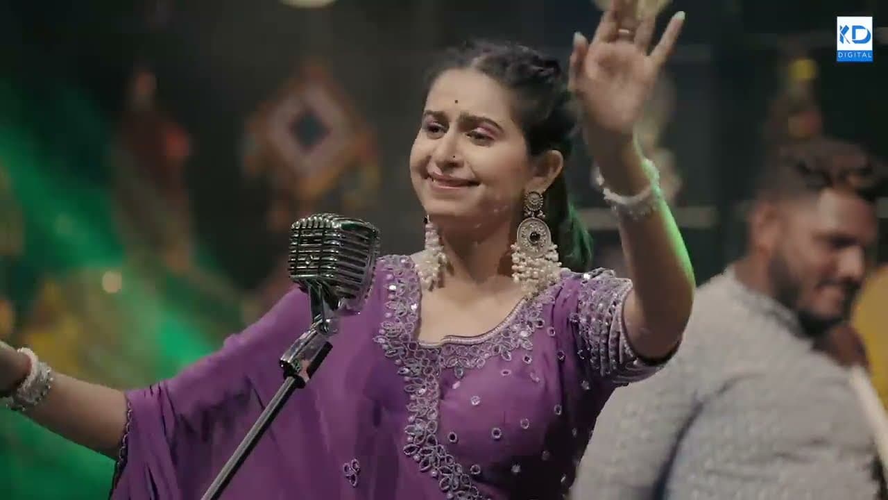 Kinjal Dave performing with her hand raised on a purple-lit stage